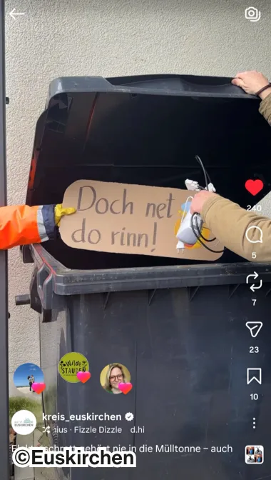 Eine offene Mülltonne mit einem Schild mit der Aufschrift "Doch net do rinn!"