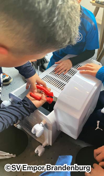 Ein Kind vom Verein SV Empor Brandenburg, das ein E-Schrott-Altgerät aufschraubt.