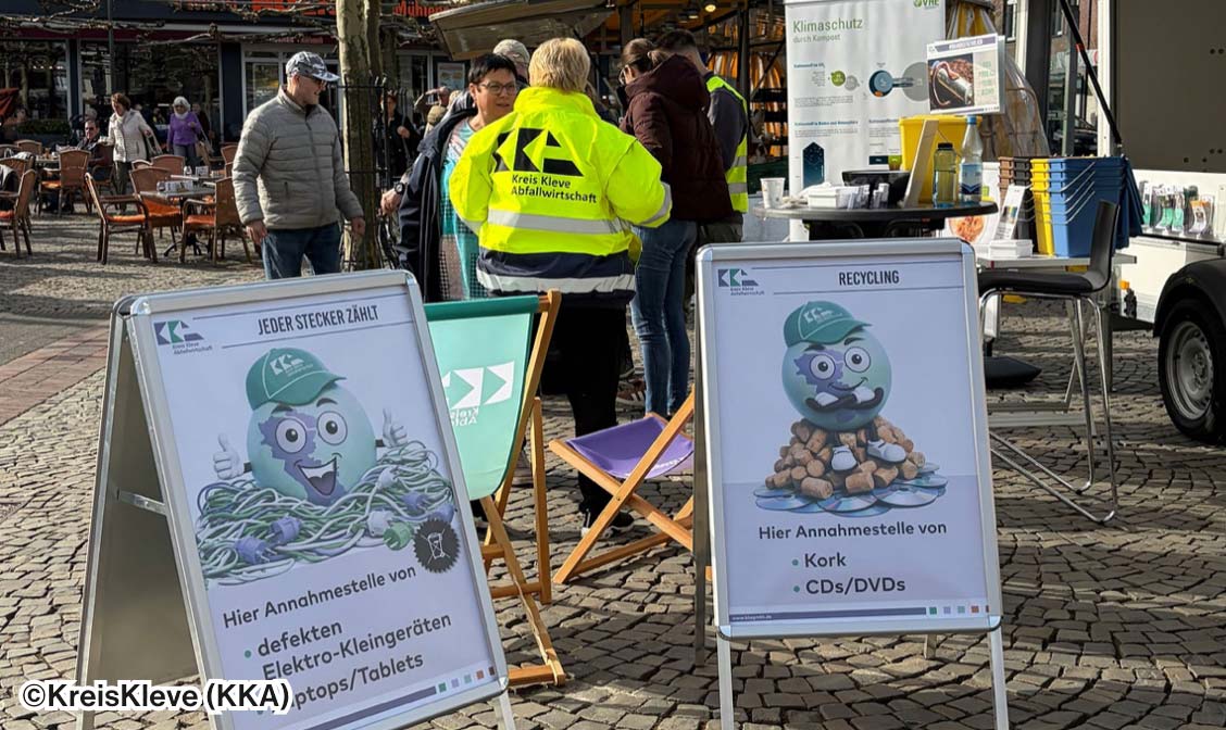 Zwei große Plakate, die vor dem Stand der Aktionen standen: eines bewirbt eine Annahmestelle für Elektro-Geräte und eines eine Annahmestelle für Kork und CDs.